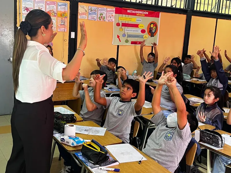 Profesora y estudiantes con las manos en alto durante una clase