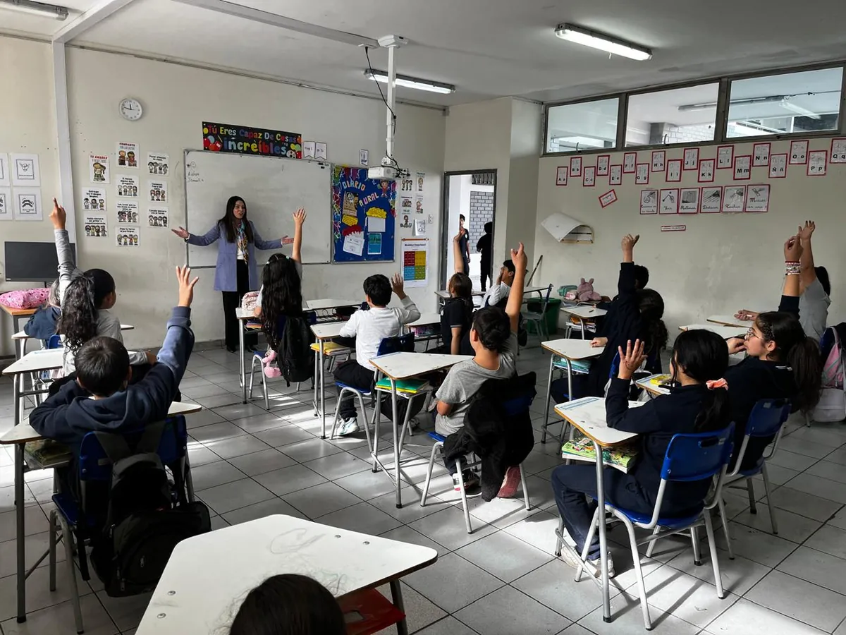 Estudiantes levantando la mano en una sala de clases