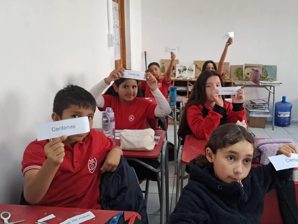 Estudiantes sonrientes mostrando tarjetas con números