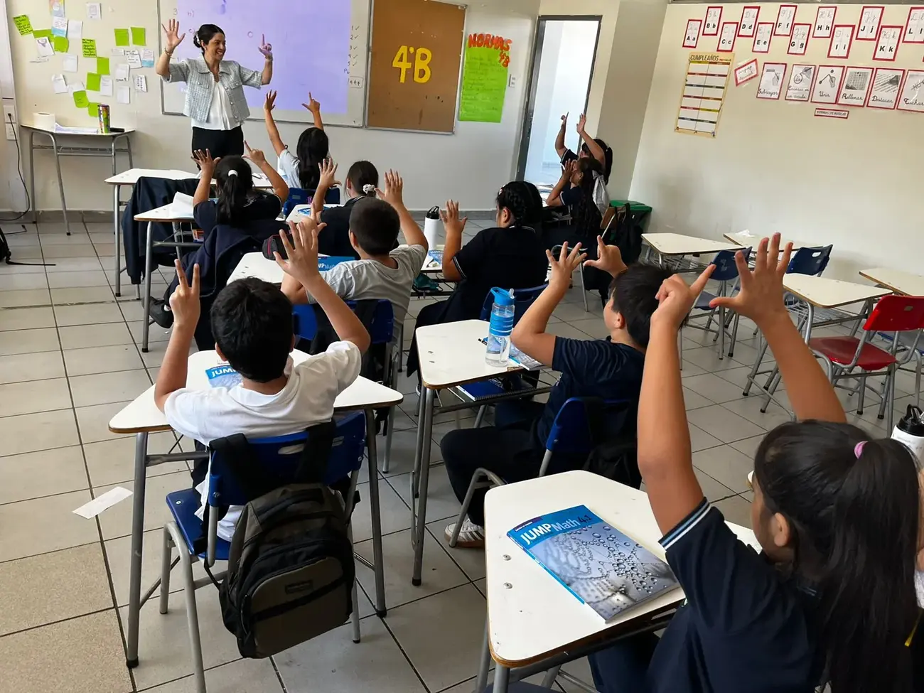 Profesora al frente y curso con las manos en alto durante una clase de JUMP Math